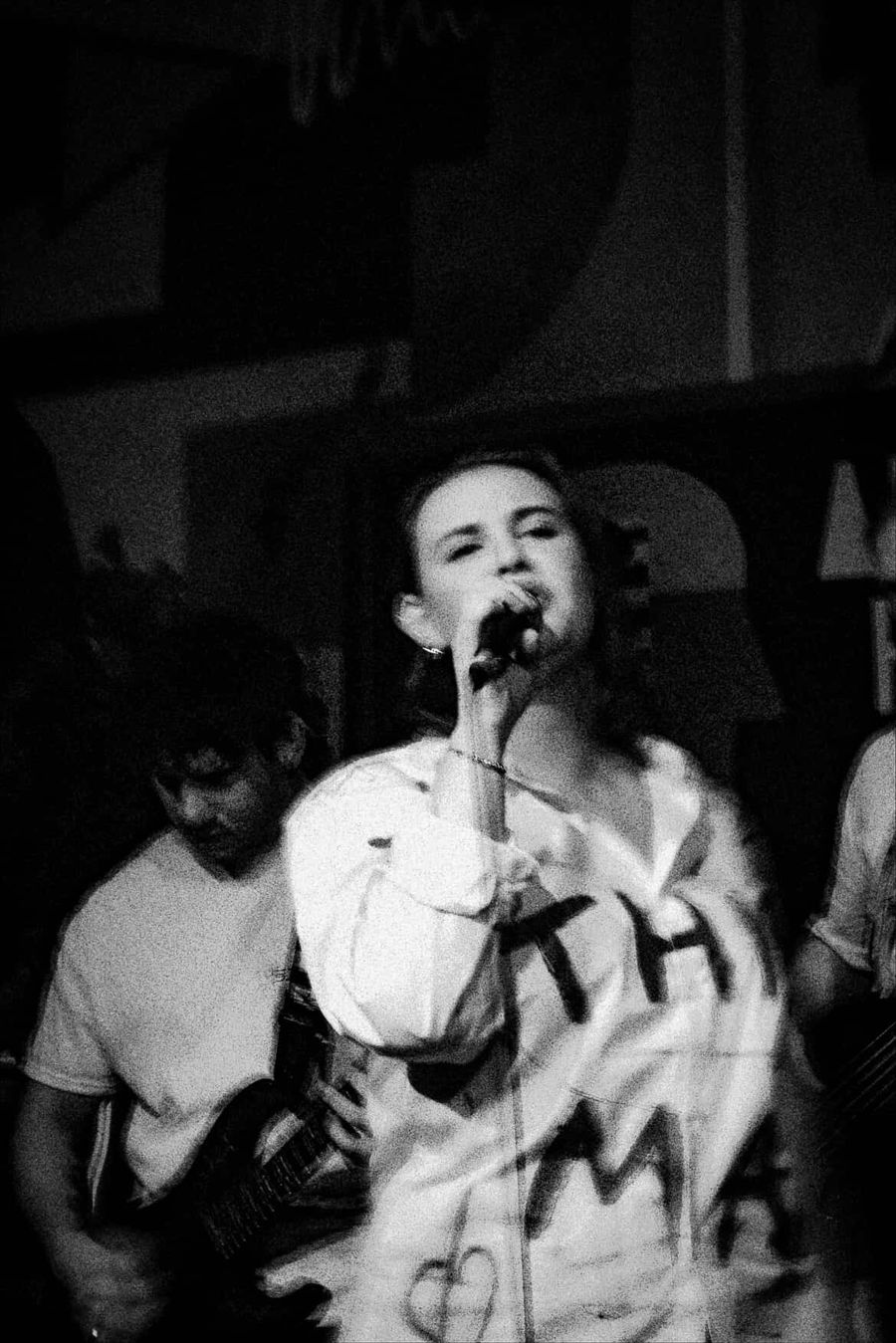Black and white photo of Fifi singing in a This Man shirt